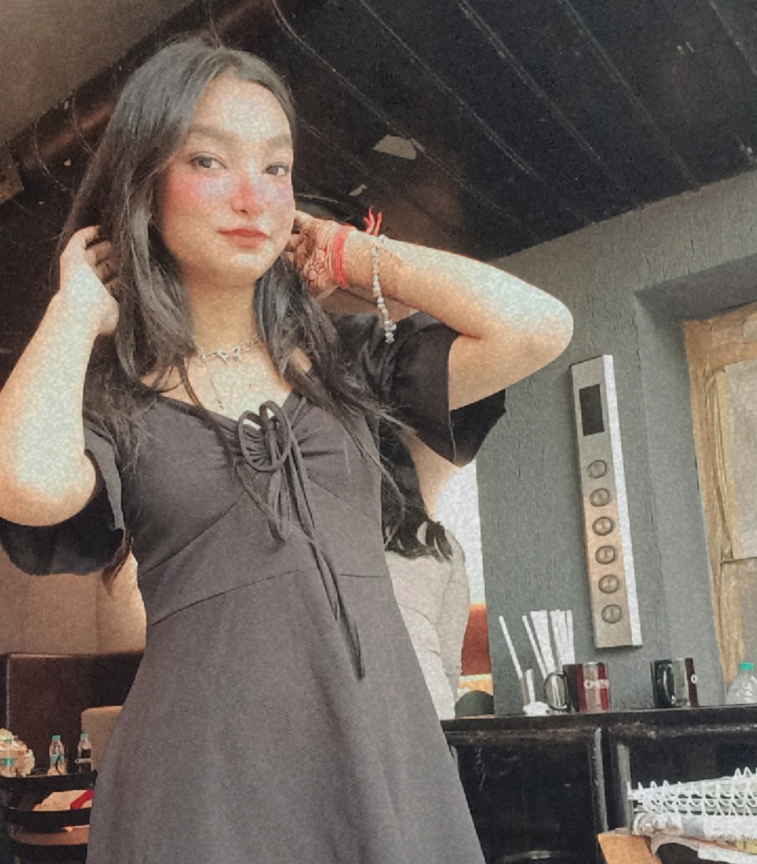 Tanya in a black tie-front dress, adjusting her hair with effortless confidence